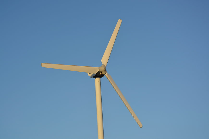 White Wind Turbine Against Clear Blue Sky