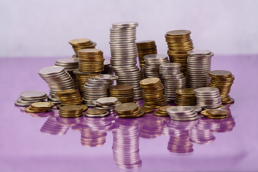 Stacks of silver and gold coins on a reflective purple surface