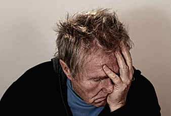 Senior man holding head in despair and exhaustion