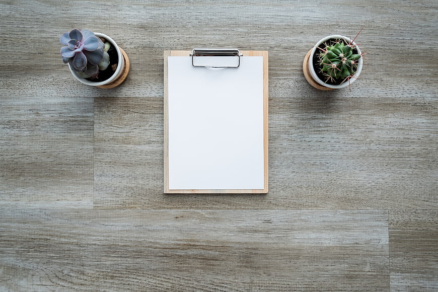 Top View of Clipboard with Succulents on Wooden Desk