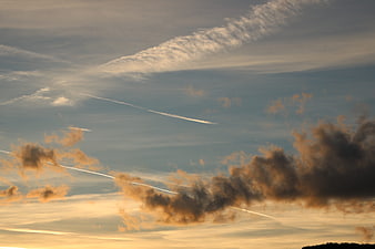 Dramatic sunset sky with contrails and scattered clouds