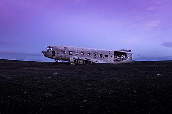 Crashed DC-3 airplane wreck on black sand beach at dusk