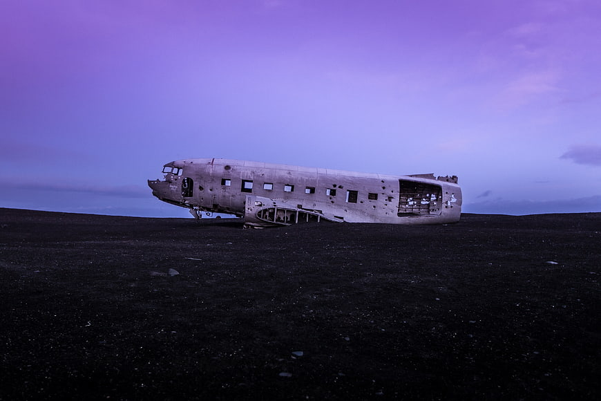 Crashed DC-3 airplane wreck on black sand beach at dusk