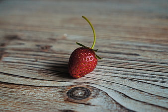 Single Red Strawberry on Rustic Wooden Table