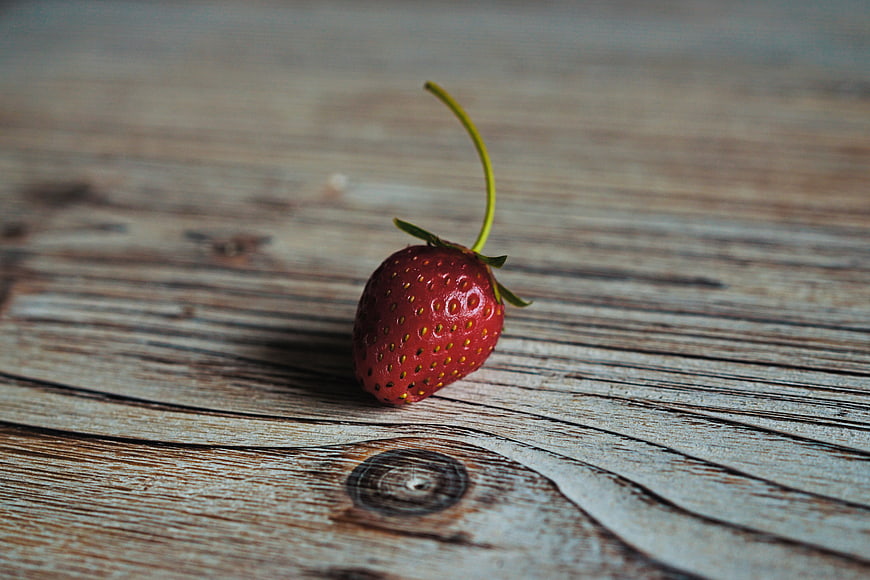 Single Red Strawberry on Rustic Wooden Table