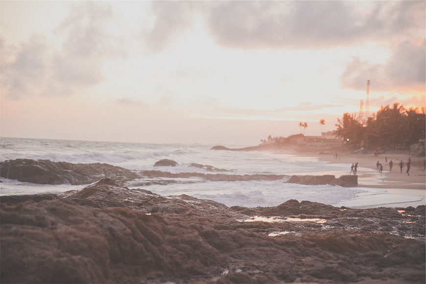 Sunset over rocky beach with ocean waves and silhouettes