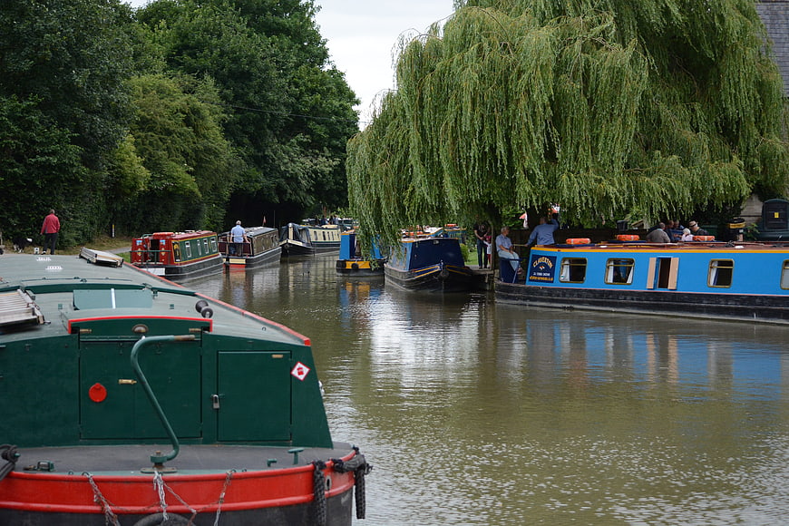 Narrowboats moored on a canal with weeping willow trees