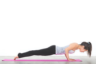 Woman doing plank exercise on pink yoga mat
