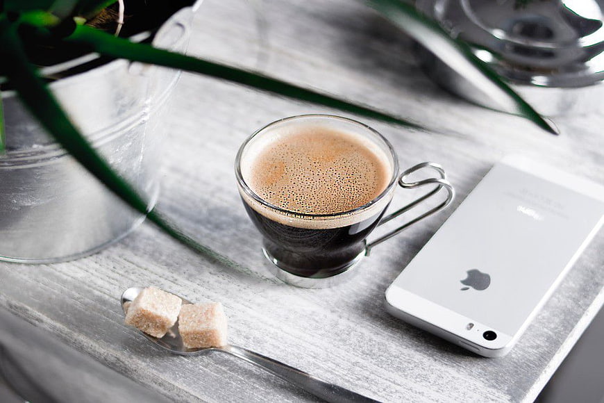Black Coffee, Smartphone, and Sugar Cubes on Wooden Desk