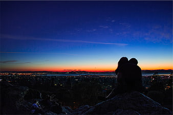 Silhouette of couple watching sunset over city skyline