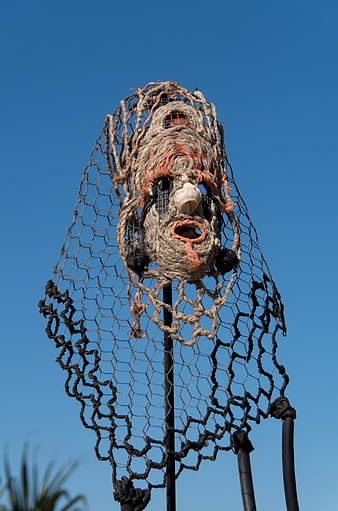 Contemporary Sculpture of Knotted Rope Head on Pole Against Blue Sky