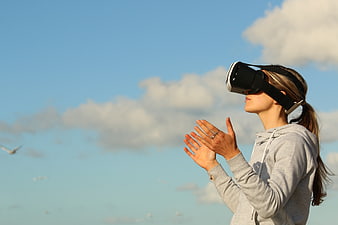 Woman Using VR Headset Outdoors Against Blue Sky