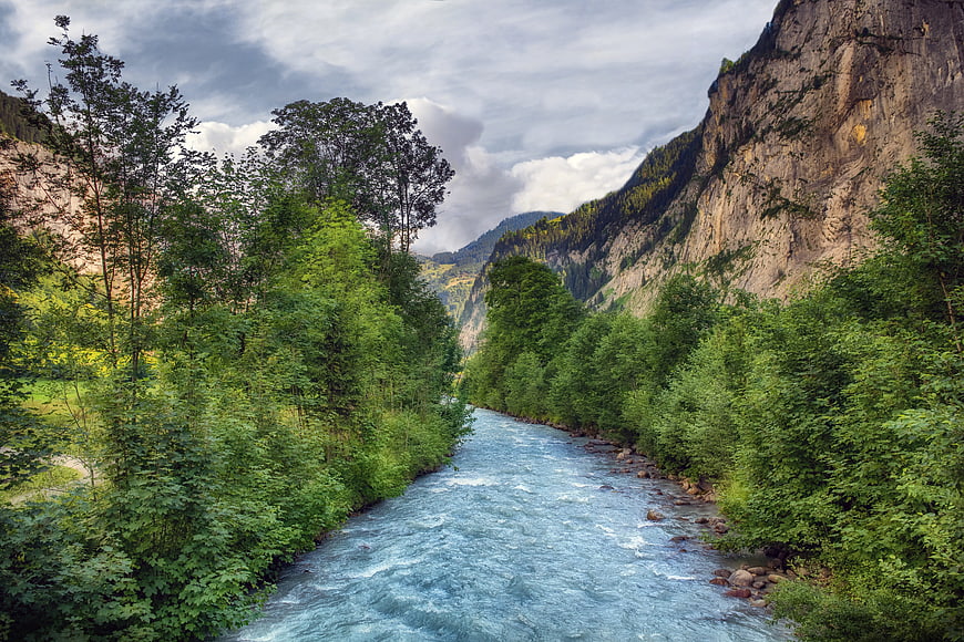 Majestic Alpine River Flowing Through Lush Green Canyon Landscape