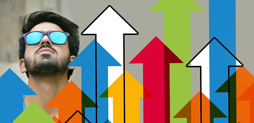 Man with sunglasses looking up at colorful growth arrows