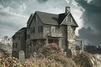 Gothic stone house in mountain graveyard with stormy sky