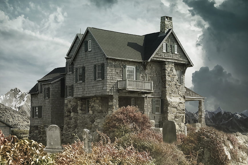 Gothic stone house in mountain graveyard with stormy sky