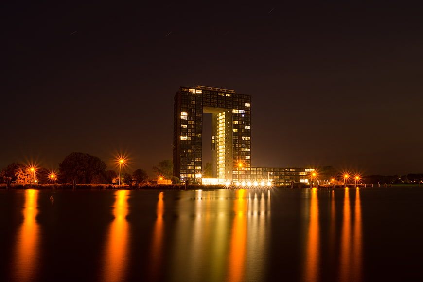 Modern square building with hole reflecting in water at night