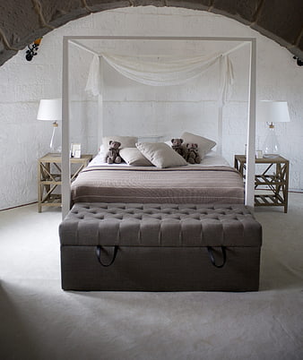 Elegant white bedroom with four-poster bed and stone archway