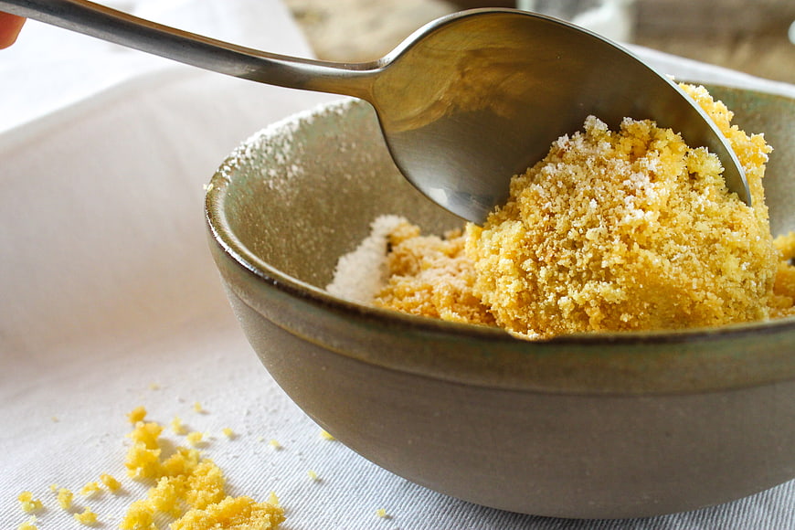 Close-up of yellow cornmeal in ceramic bowl with spoon