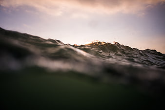 Close-up of ocean wave cresting at sunset with golden light
