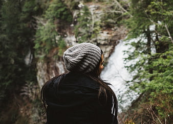 Woman in Beanie Looking at Waterfall in Forest