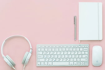 Minimalist pink workspace with white keyboard, mouse, and headphones