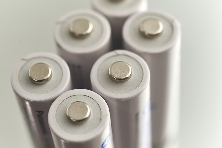 Close-up of white cylindrical battery cells with positive terminals
