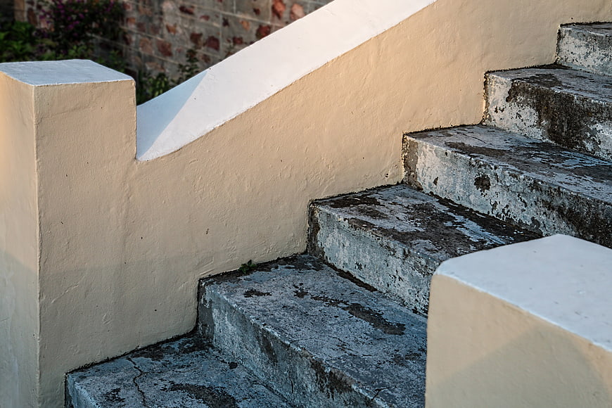 Weathered Concrete Staircase With Cream Handrail And Warm Sunlight