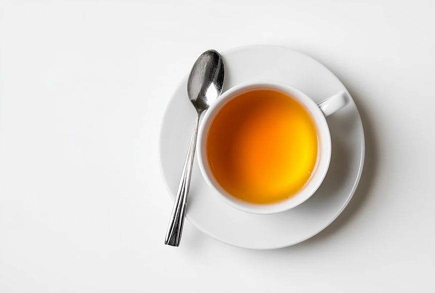 Overhead View of Amber Tea in White Cup with Spoon