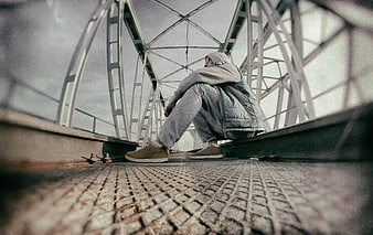 Man sitting alone on metal bridge structure