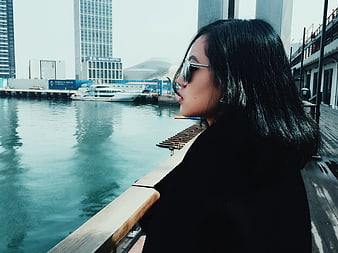 Woman in sunglasses looking at city waterfront