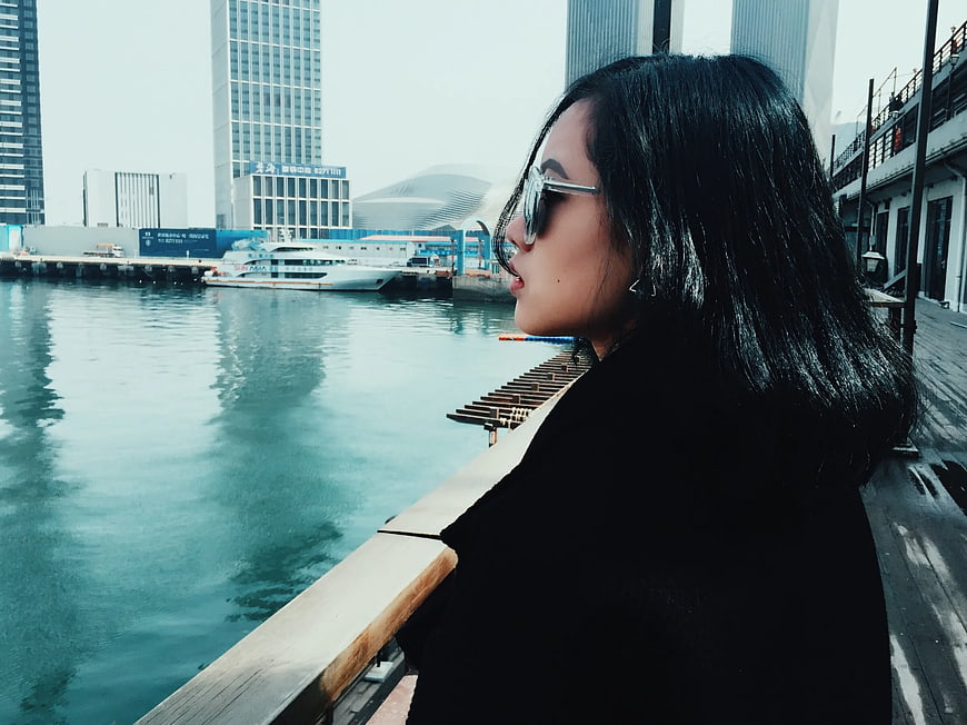 Woman in sunglasses looking at city waterfront
