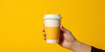 Hand holding coffee cup on yellow background
