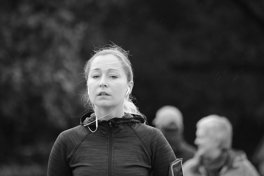 Grayscale Portrait of Woman Running in Rain with Earbuds