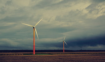 Wind turbines in a field under a dramatic cloudy sky