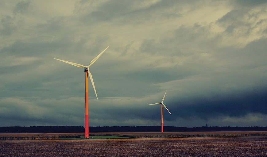 Wind turbines in a field under a dramatic cloudy sky