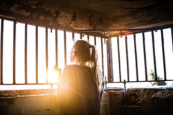 Woman Looking Through Prison Bars at Sunset
