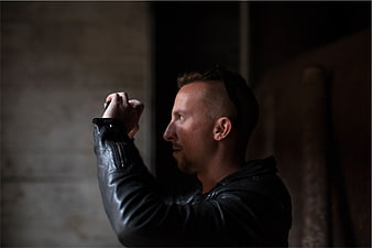 Man in Leather Jacket Taking Photo in Dark Setting