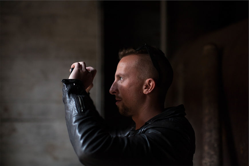 Man in Leather Jacket Taking Photo in Dark Setting