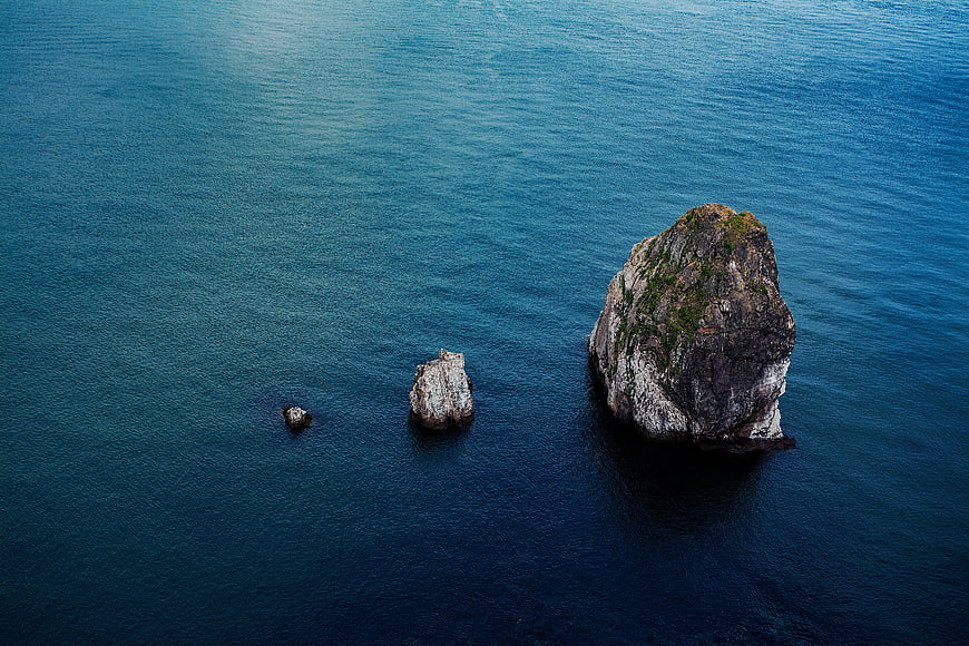 Aerial View of Three Rocks in Deep Blue Ocean Water