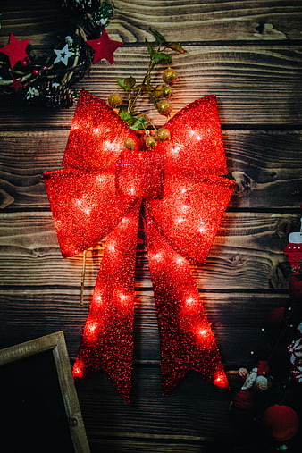 Glowing Red Glitter Christmas Bow on Wooden Background