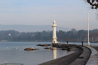 White Lighthouse on Lake Shore with Mountains