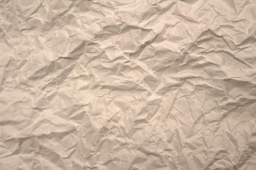 Crumpled beige paper texture background with wrinkles and folds