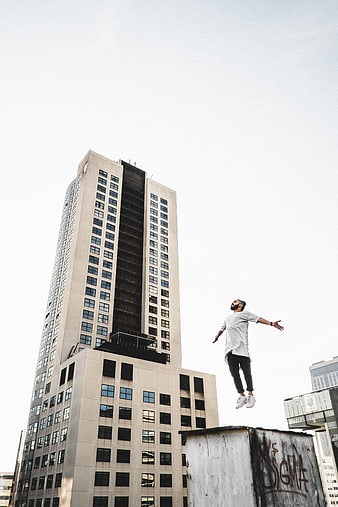 Man Jumping on Rooftop with Skyscraper Background