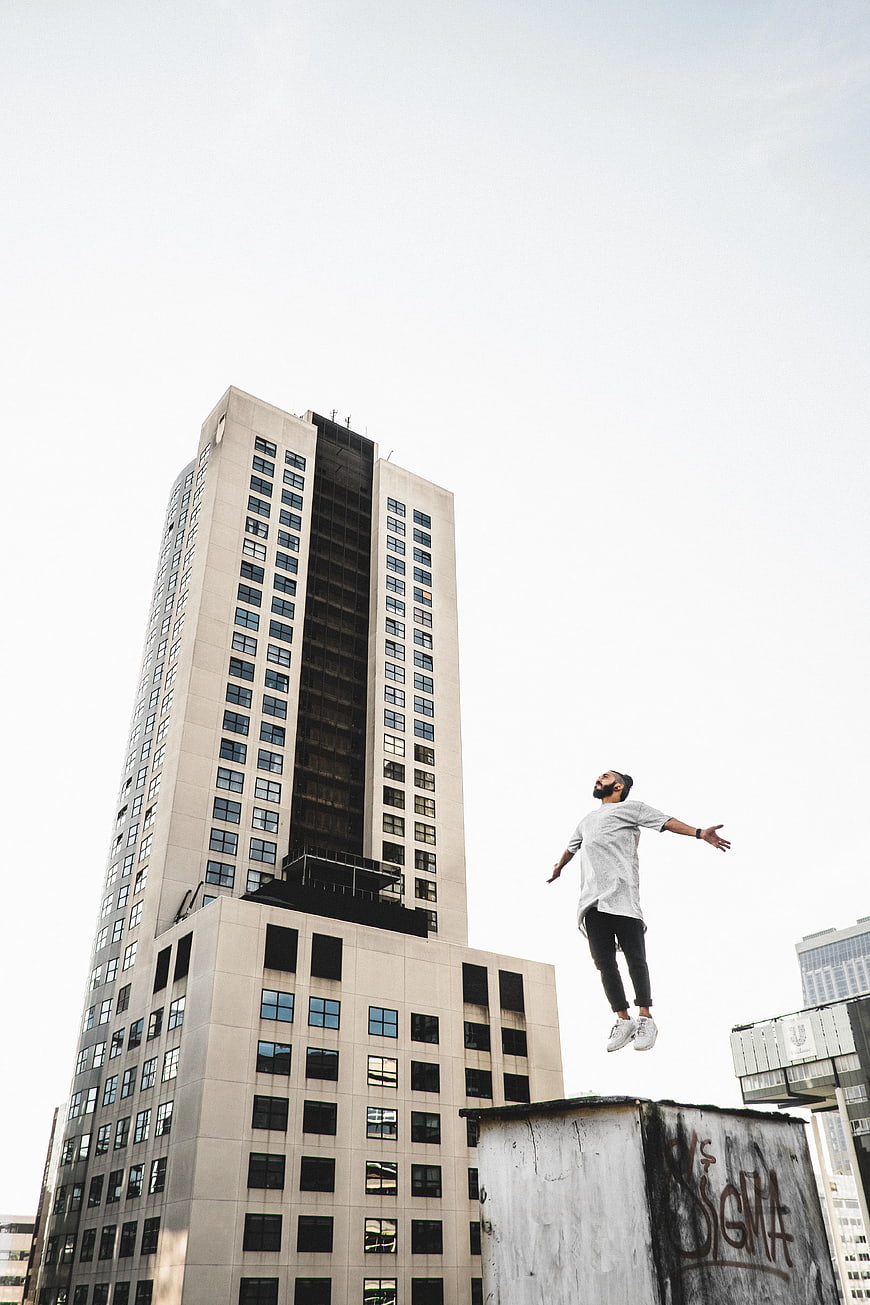 Man Jumping on Rooftop with Skyscraper Background