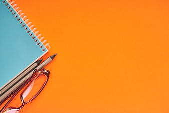 Blue Notebook, Pencils, and Glasses on Orange Background