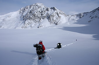 Hikers trekking through deep snow in alpine winter landscape