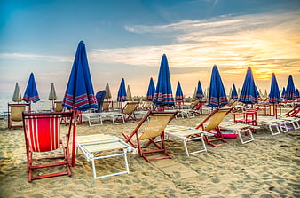 Empty Beach Chairs and Blue Umbrellas at Sunset