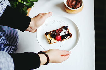 Hands holding plate of fruit toast breakfast