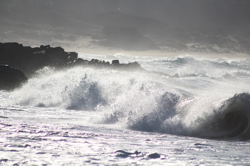 Powerful ocean wave crashing against dark rocky coastline